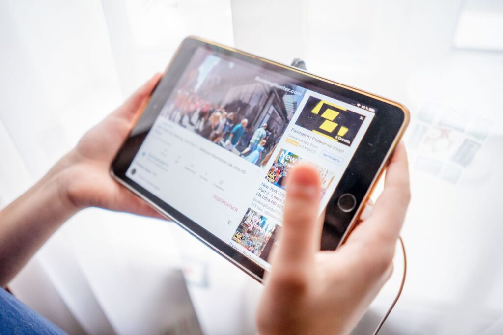 Close-up of hands holding a tablet device browsing online content indoors.